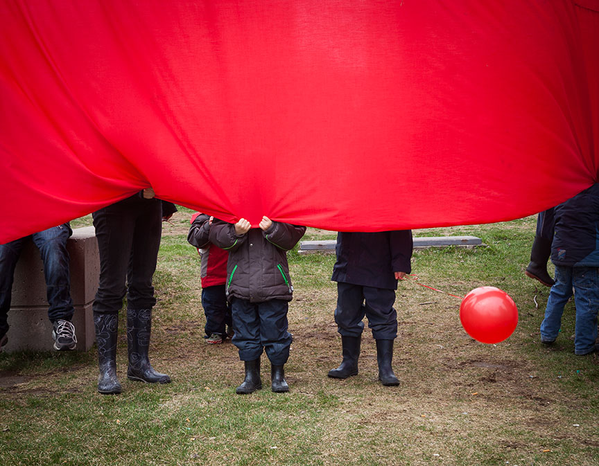Editorial photo of kids playing with a red balloon and red fabric in a park by Marili Clark Photographer.