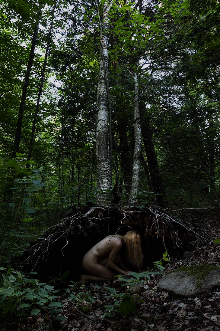 Le Repos de la Guerrière - La Matrice - Woman kneeling under the roots of fallen birch trees.