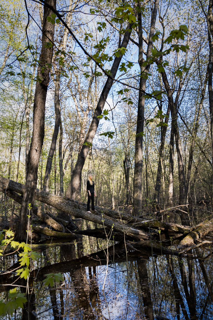 Le Repos de la Guerrière - Reflection - Woman in black suit standing on a fallen tree in a swamp.