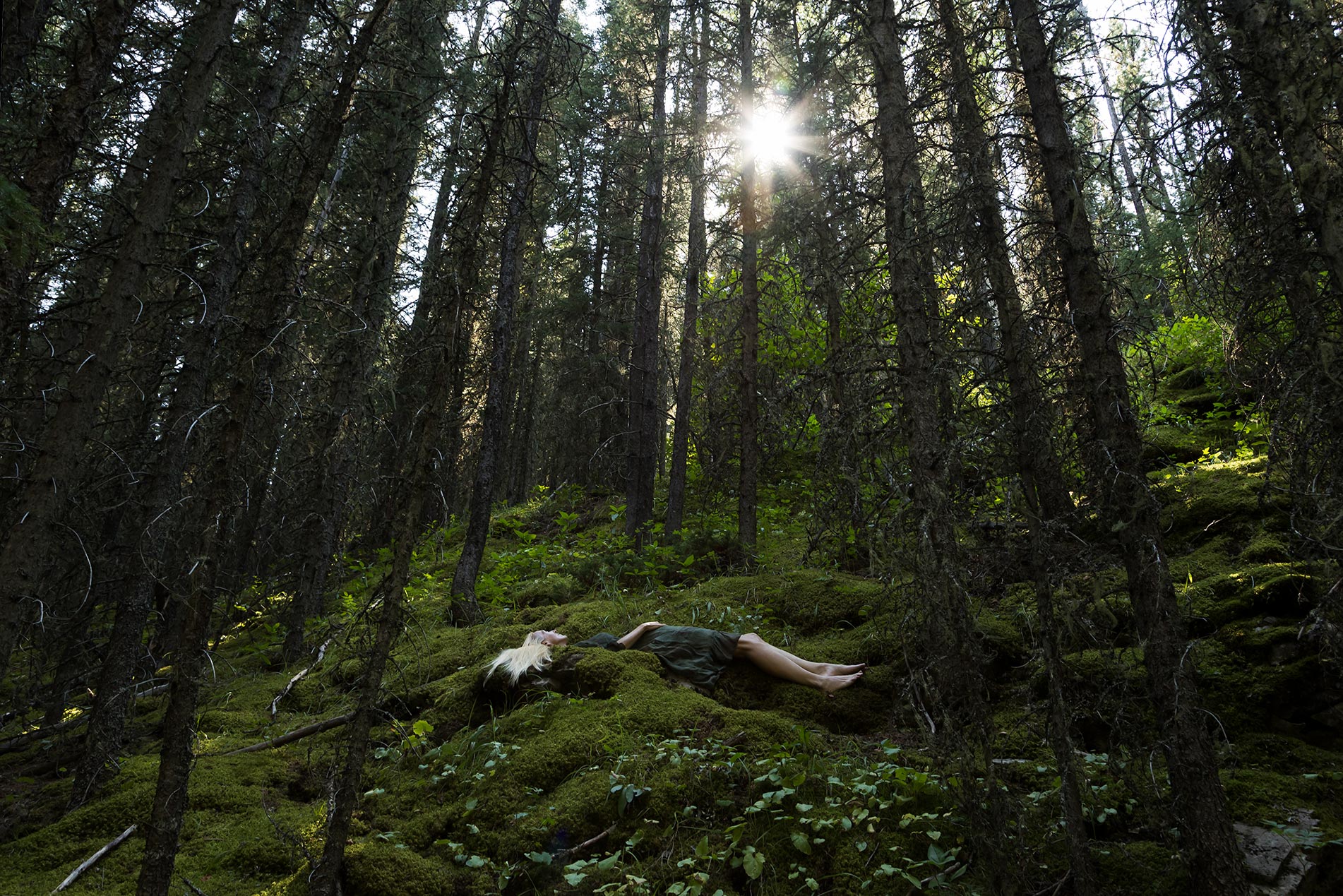 Le Repos de la Guerrière - Mousse Mémoire - Woman in green dress resting on a bed of green moss in a forest.